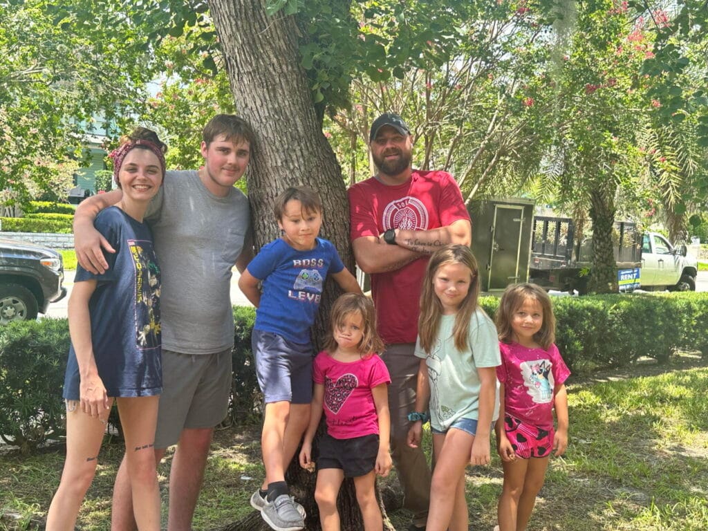 Pastor Jon and his family gathered under a large oak tree